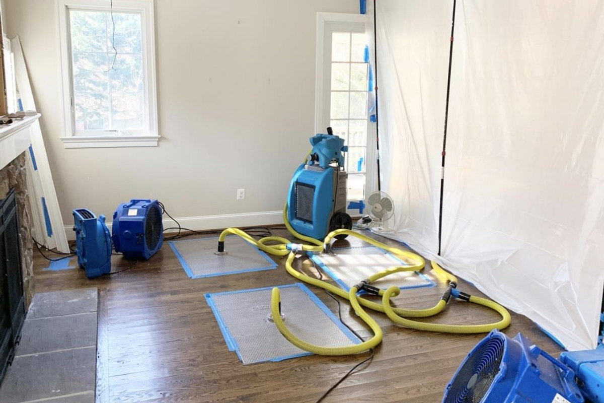 Technician assessing moisture near an indoor wall and floor